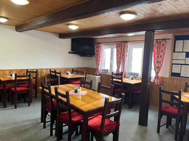 Restaurace s dřevěnými stoly a červenými židlemi